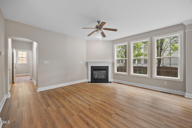 120 Hatchet Creek Ct, Morrisville, NC 27560 - unfurnished living room with arched walkways, a ceiling fan, wood finished floors, a fireplace with flush hearth, and baseboards