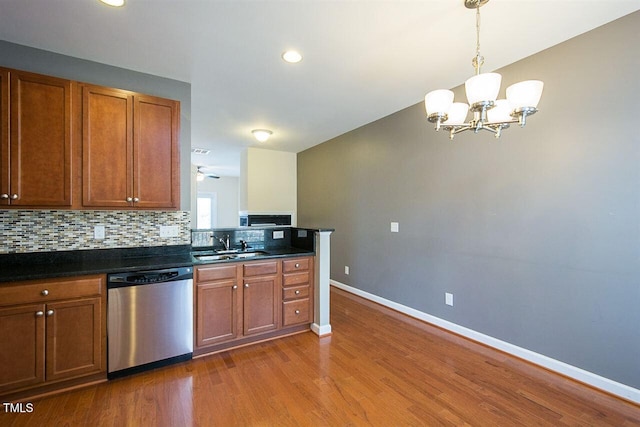 8016 Sycamore Hill Ln, Raleigh, NC 27612 - kitchen with wood finished floors, dark countertops, a notable chandelier, backsplash, and dishwasher