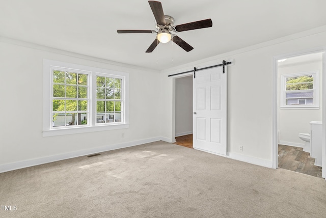 183 Red Hill Loop Rd, Warrenton, NC 27589 - unfurnished bedroom with carpet flooring, a barn door, baseboards, and multiple windows