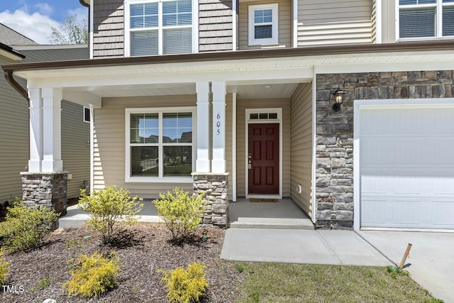 property entrance with stone siding, a garage, and a porch