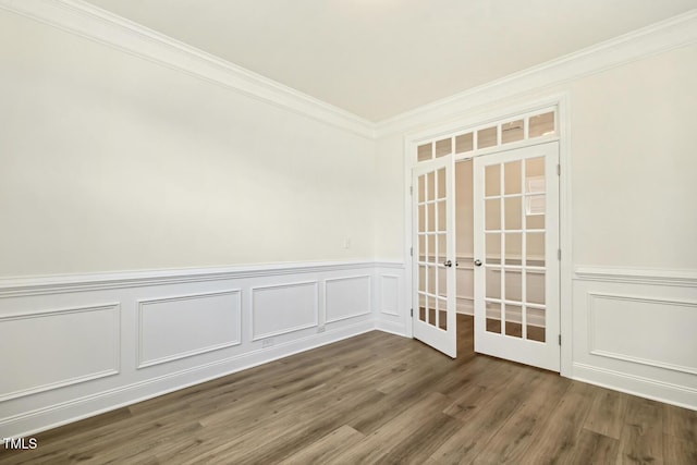 unfurnished room with french doors, ornamental molding, a decorative wall, wainscoting, and dark wood finished floors