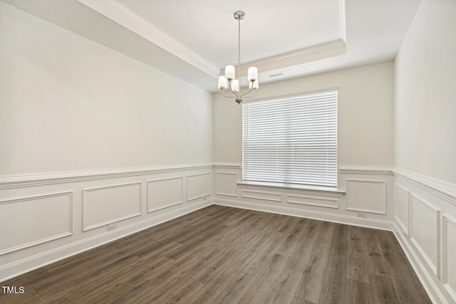 unfurnished dining area featuring a chandelier, crown molding, wainscoting, dark wood-type flooring, and a decorative wall