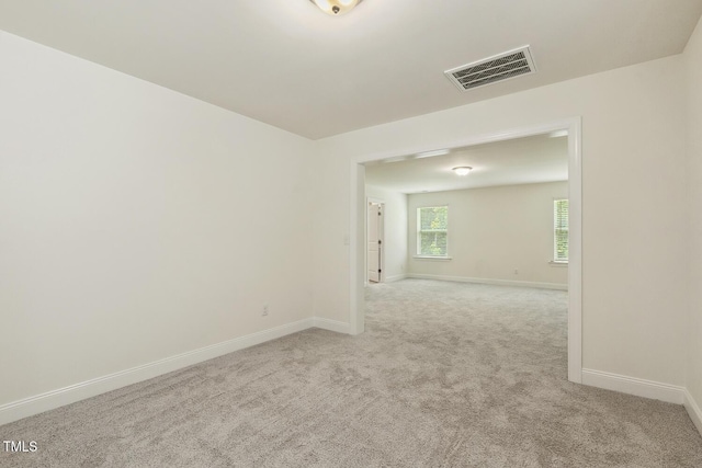 empty room featuring baseboards and light carpet