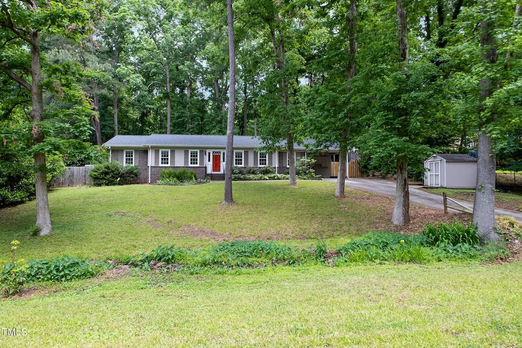 ranch-style house with asphalt driveway, a storage shed, an outdoor structure, and a carport