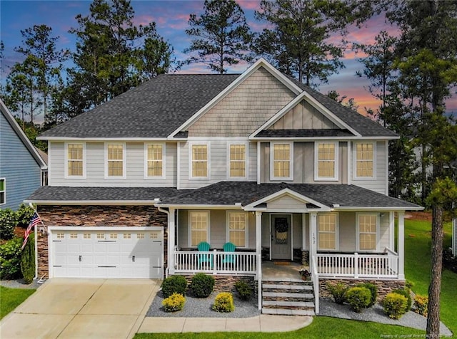 craftsman house with covered porch, roof with shingles, stone siding, concrete driveway, and a garage