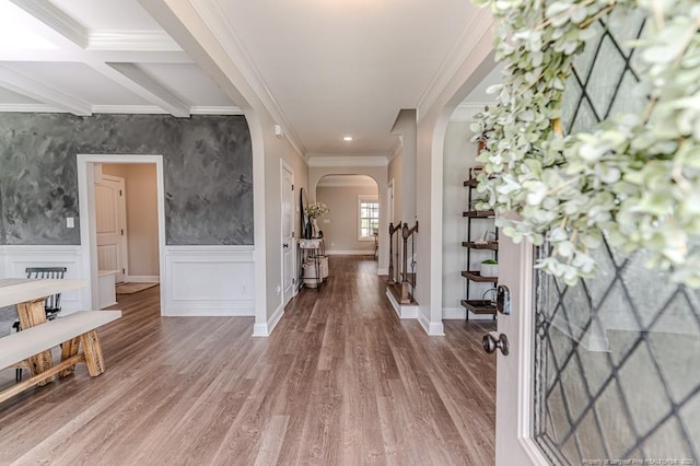 entrance foyer with wood finished floors, a wainscoted wall, crown molding, baseboards, and arched walkways