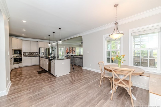 kitchen with dark countertops, stainless steel appliances, open floor plan, crown molding, and baseboards