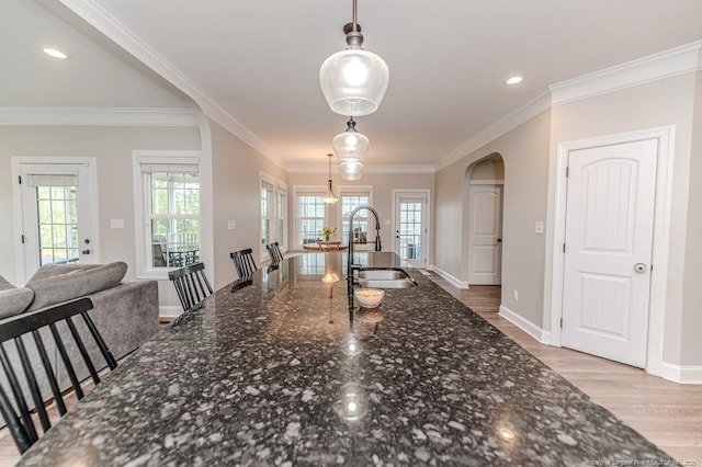 dining area with recessed lighting, baseboards, ornamental molding, light wood finished floors, and arched walkways
