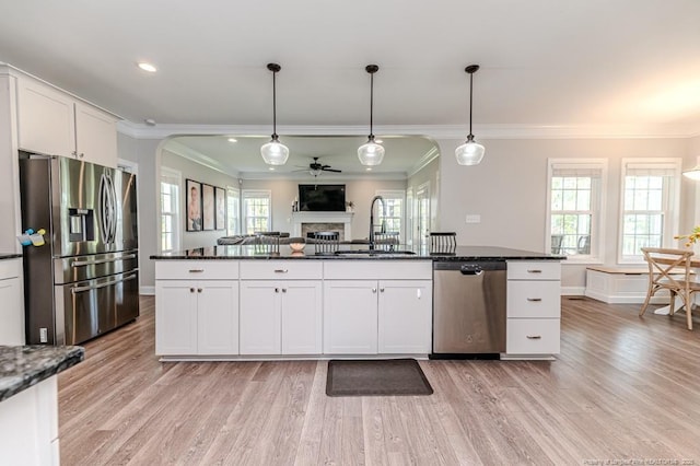 kitchen with arched walkways, ornamental molding, stainless steel appliances, and a sink