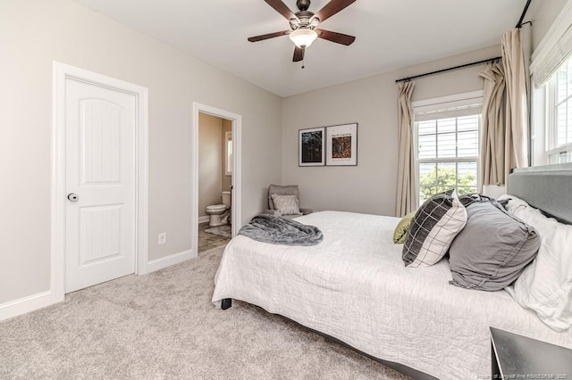 bedroom with ceiling fan, ensuite bathroom, carpet floors, and baseboards