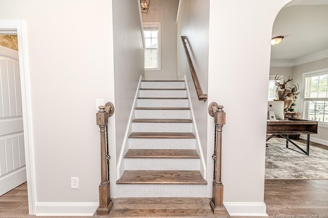 stairs with baseboards, crown molding, and wood finished floors