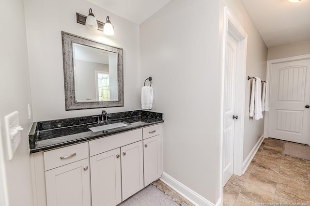 bathroom featuring baseboards, vanity, and stone finish floor