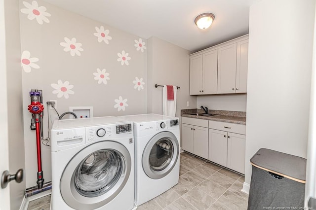 laundry room with independent washer and dryer, cabinet space, and a sink