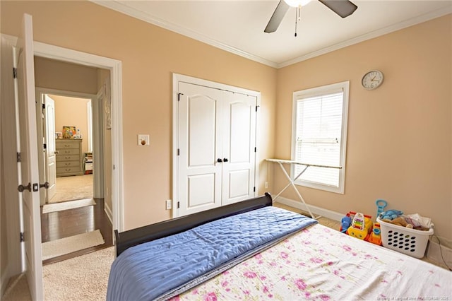 carpeted bedroom featuring crown molding, a closet, baseboards, and ceiling fan
