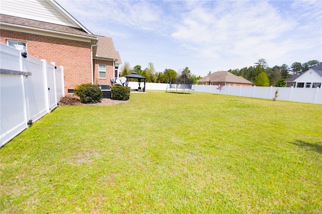 view of yard featuring a fenced backyard, a gazebo, and a trampoline