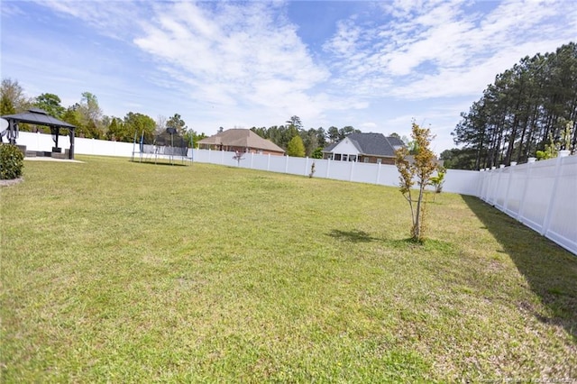 view of yard featuring a trampoline, a gazebo, and a fenced backyard
