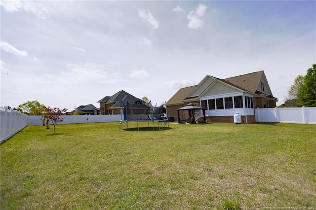 view of yard featuring a sunroom, a trampoline, a gazebo, and a fenced backyard