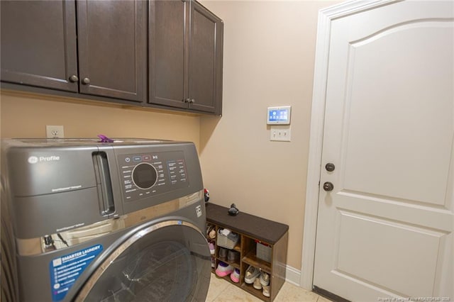 washroom featuring washer / clothes dryer, cabinet space, baseboards, and light tile patterned floors