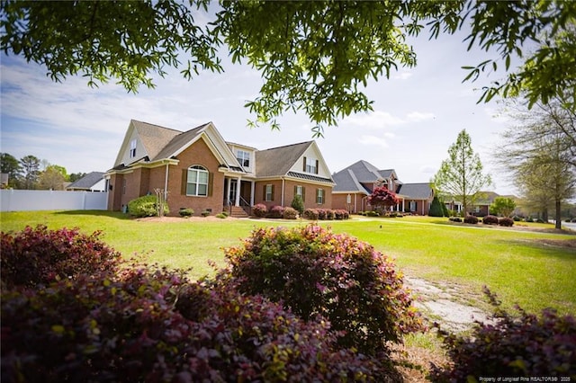 view of front facade featuring a front lawn, brick siding, and fence
