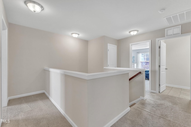 corridor with an upstairs landing, light colored carpet, and baseboards