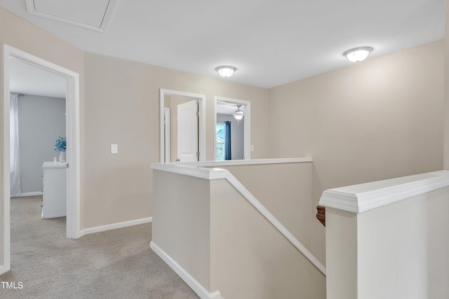 hall featuring an upstairs landing, carpet flooring, and baseboards