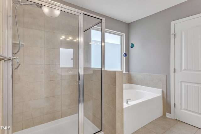 bathroom featuring a stall shower, a bath, and tile patterned floors
