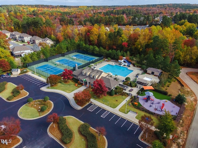 drone / aerial view of a pool and a heavily wooded area