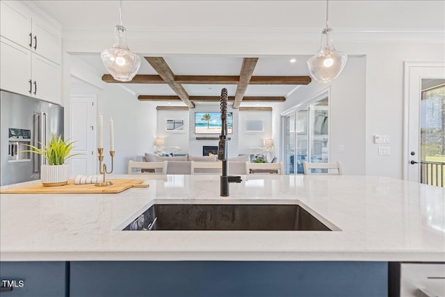 kitchen featuring open floor plan, a sink, light stone countertops, coffered ceiling, and beam ceiling