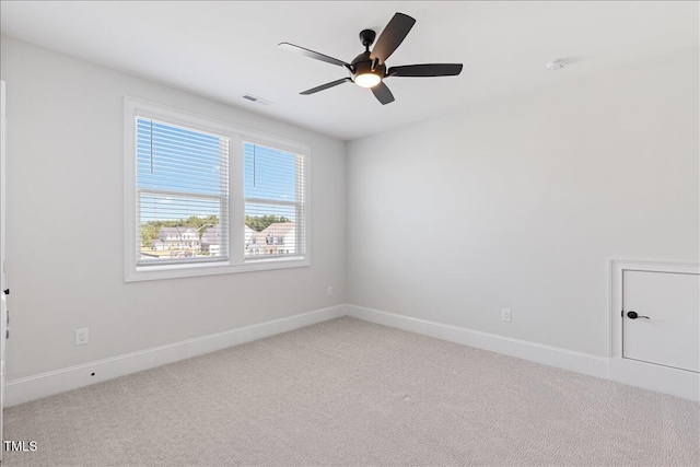 empty room featuring light colored carpet, a ceiling fan, and baseboards