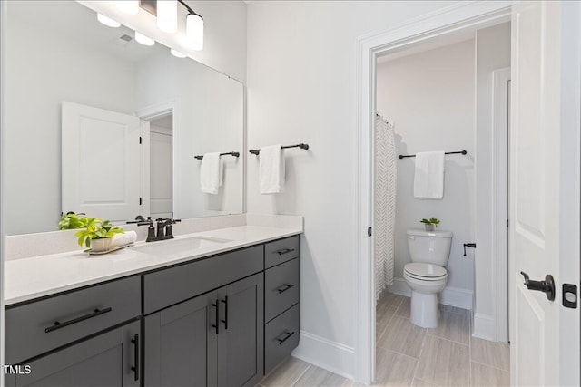 full bath featuring toilet, vanity, and baseboards