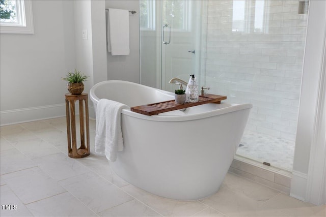full bath featuring a stall shower, a soaking tub, marble finish flooring, and baseboards