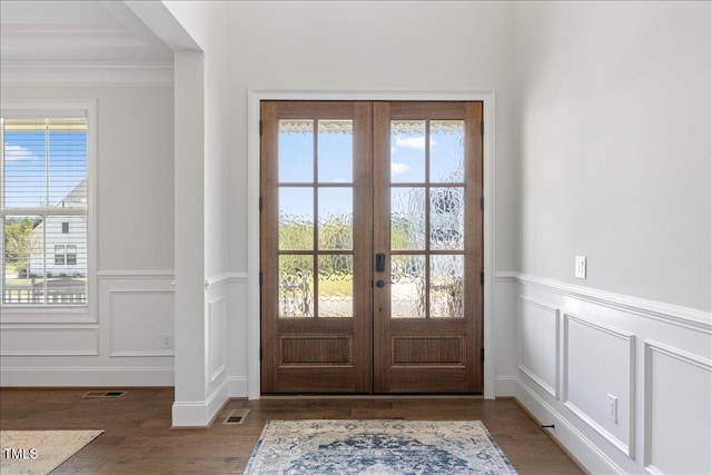entryway with french doors, a decorative wall, wainscoting, wood finished floors, and crown molding