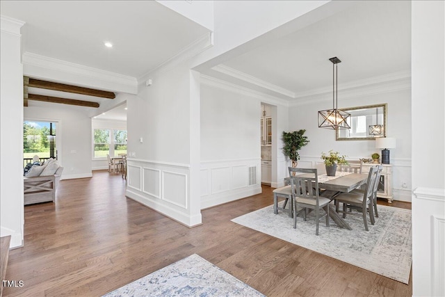 dining room featuring wood finished floors, ornamental molding, a wainscoted wall, beam ceiling, and recessed lighting