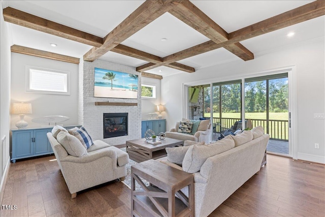 living room with healthy amount of natural light, dark wood-style floors, beam ceiling, a brick fireplace, and coffered ceiling