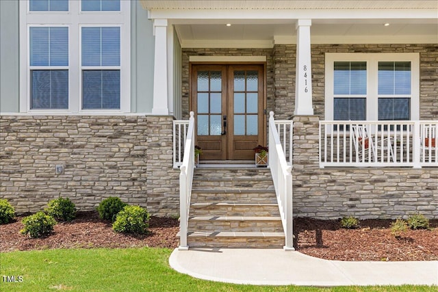 property entrance with stone siding, french doors, and covered porch