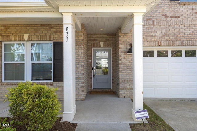 833 Ember Dr, Durham, NC 27703 - doorway to property with brick siding, covered porch, and an attached garage