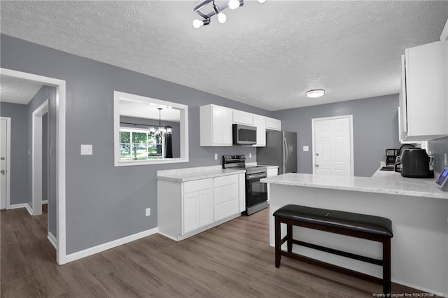 1618 Hickory Ridge Ct, Fayetteville, NC 28304 - kitchen with appliances with stainless steel finishes, dark wood finished floors, a textured ceiling, white cabinetry, and a peninsula