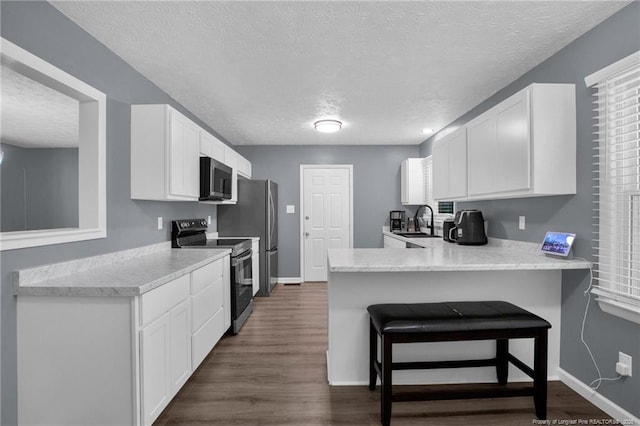 1618 Hickory Ridge Ct, Fayetteville, NC 28304 - kitchen featuring stainless steel appliances, a textured ceiling, a sink, a peninsula, and white cabinetry