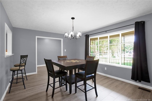 1618 Hickory Ridge Ct, Fayetteville, NC 28304 - dining area featuring a chandelier, a textured ceiling, wood finished floors, and baseboards