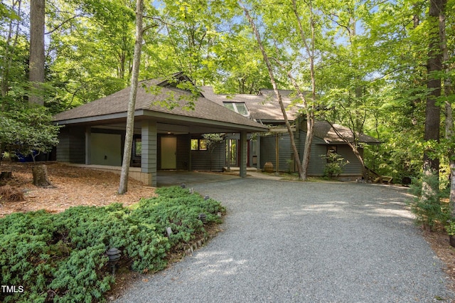 view of front facade featuring driveway, roof with shingles, and a carport