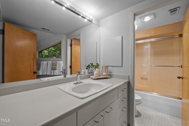 full bathroom featuring toilet, tile patterned floors, vanity, and enclosed tub / shower combo