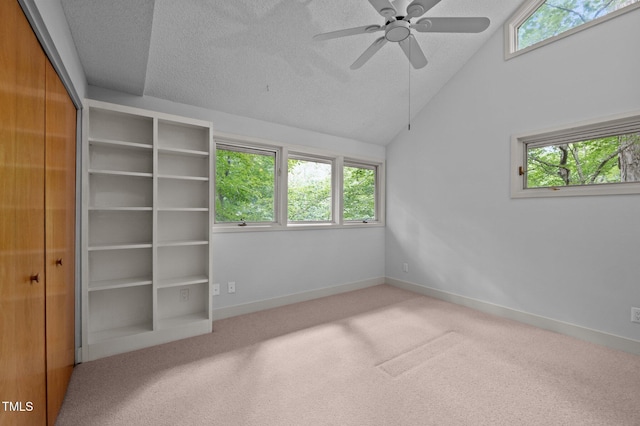 unfurnished bedroom featuring carpet, a textured ceiling, baseboards, a closet, and vaulted ceiling