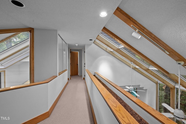 corridor with a textured ceiling, light carpet, baseboards, recessed lighting, and plenty of natural light