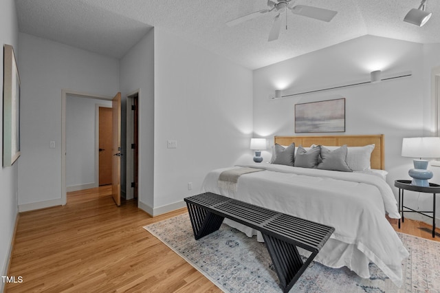 bedroom featuring a textured ceiling, light wood-type flooring, lofted ceiling, baseboards, and ceiling fan