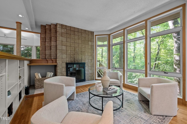 living area featuring plenty of natural light, wood finished floors, a fireplace, and a textured ceiling