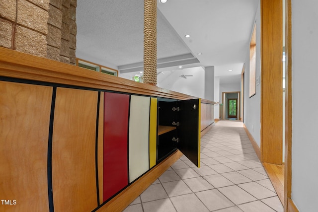 hallway featuring light tile patterned floors, recessed lighting, a textured ceiling, and baseboards