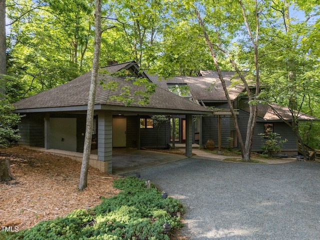 view of front of home with a shingled roof, driveway, and an attached carport