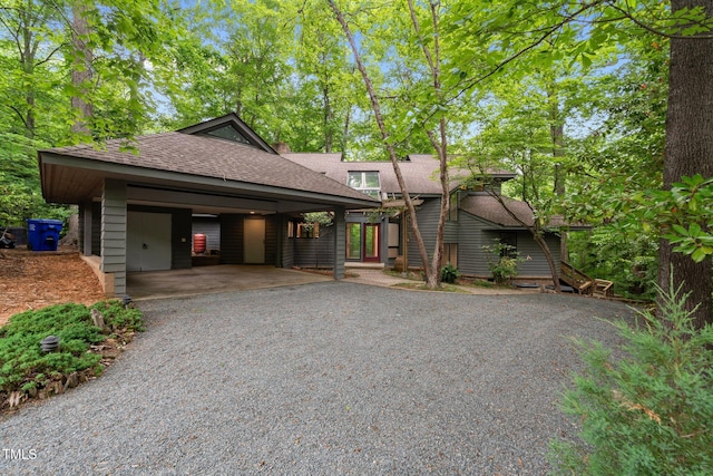 view of front of house featuring roof with shingles, driveway, and a carport