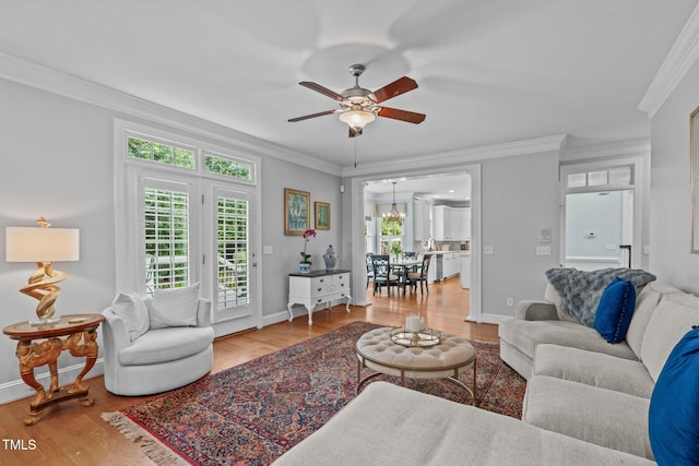 living room featuring ornamental molding, wood finished floors, a ceiling fan, and baseboards