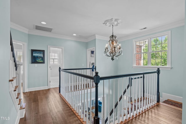hall with a chandelier, plenty of natural light, baseboards, hardwood / wood-style flooring, and crown molding